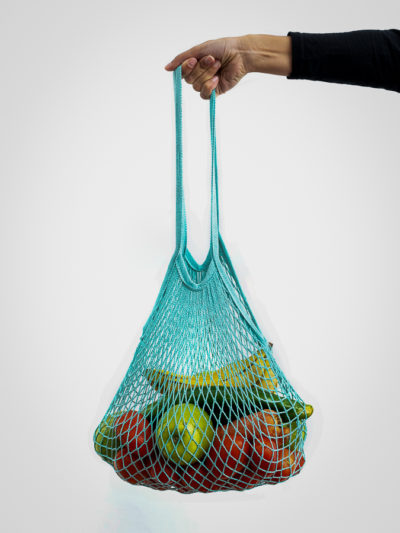 Girl holding reusable mesh bag full of organic vegetables