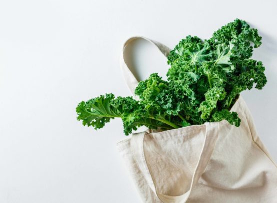 Fresh Kale leaves in a canvas bag. Eco friendly shopping. Healthy product. Top view, copy space.